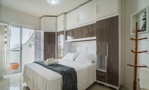 Une chambre à coucher avec un lit, une armoire et une petite étagère.