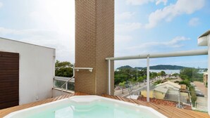 Un jacuzzi en un balcón con vista a una masa de agua y edificios circundantes.