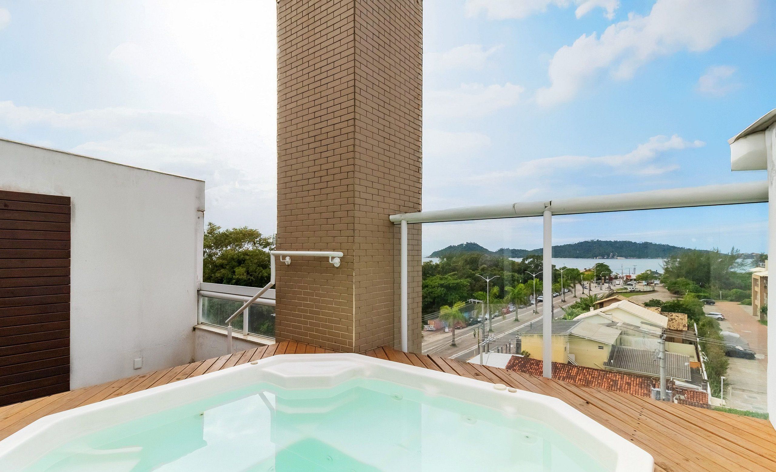 A hot tub on a balcony with a view of a body of water and surrounding buildings.