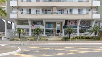 Un edificio de varios pisos con una planta baja comercial que alberga diferentes negocios, como un banco y una tienda de conveniencia.