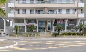 Un immeuble à plusieurs étages dont le rez-de-chaussée est occupé par des commerces, notamment une banque et une épicerie.