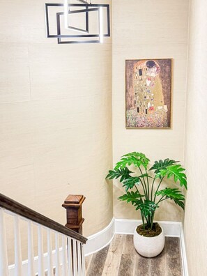 A staircase with a white railing, a wall-mounted abstract light fixture, and a framed painting. - Cozy 4BR City Escape in the Heart of Philly (Philadelphia)