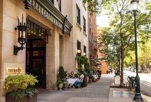 An outdoor cafe with tables and chairs, a building with a sign reading 'TOURAINE,' and a street with trees and parked bicycles. - Cozy 4BR City Escape in the Heart of Philly (Philadelphia)