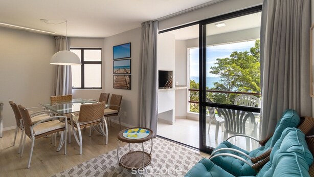 Una sala de estar moderna con una mesa de vidrio, sillas de mimbre, un sofá y vistas al exterior.