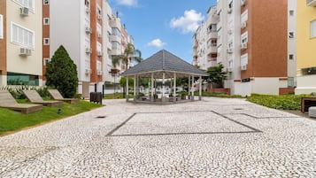 A courtyard with a gazebo, surrounded by multi-story residential buildings with balconies and air conditioning units.