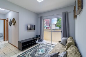 A living room with a sofa, a TV, a coffee table, and a patterned rug. - Apt With 3 Bedrooms 200m From Ufsc Elk0101 (Florianópolis)