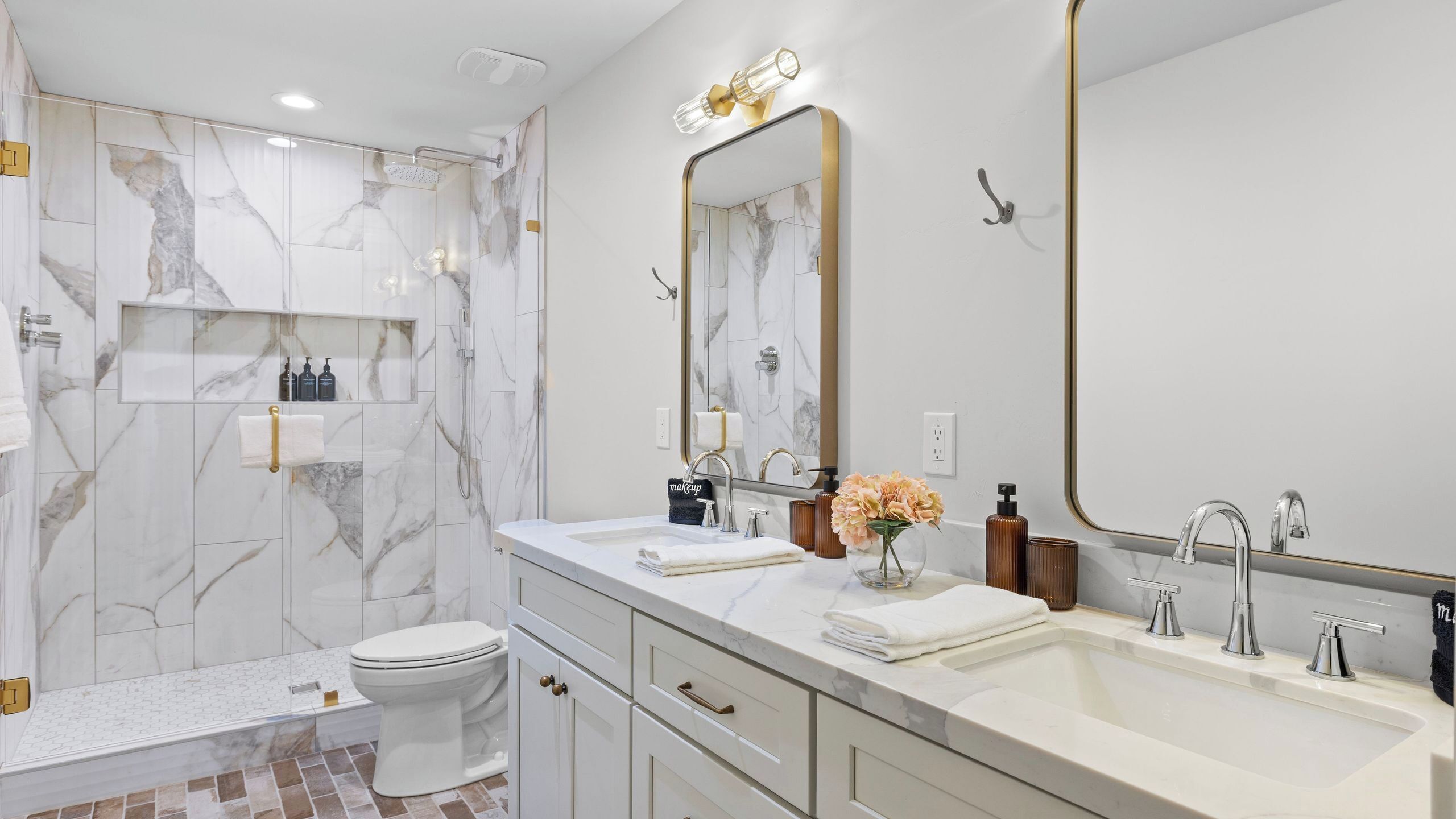 A modern bathroom with a shower, toilet, vanity with dual sinks, and a large mirror.