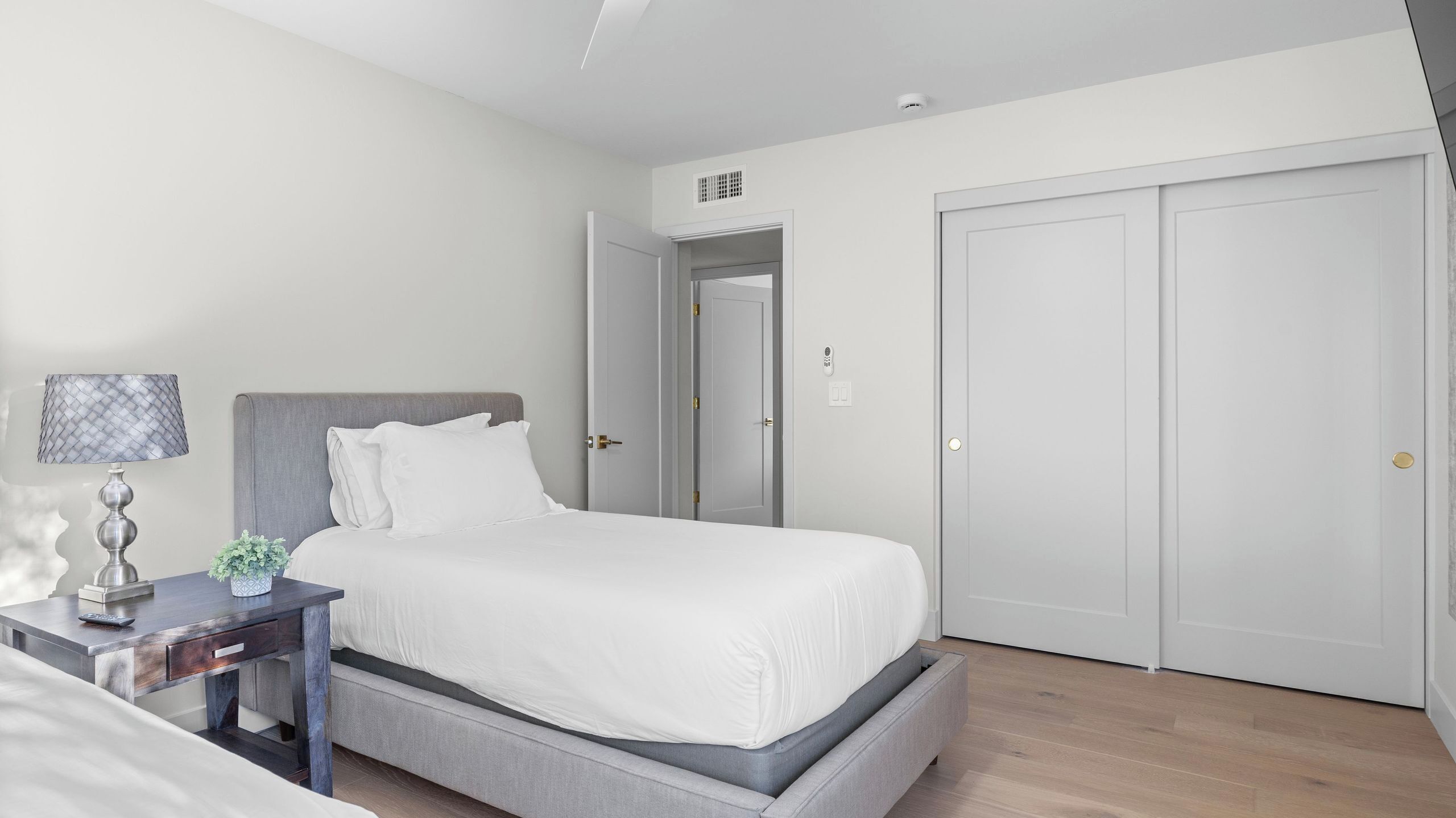 A bedroom with a bed, bedside table, lamp, and a wardrobe.