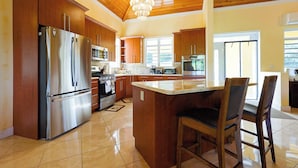 A modern kitchen with wooden cabinets, stainless steel appliances, and a large island with bar stools.