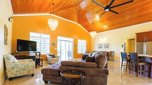A spacious living room with a large sofa, a television, and a dining area with chairs and a table.
