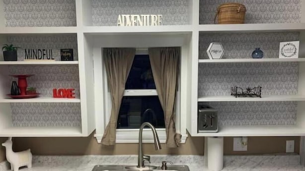A kitchen with a double sink, white cabinetry, and decorative shelves with words like "ADVENTURE" and "LOVE". - ,Fern Corner: 4 bedroom / 2 Bath (Stillwater)