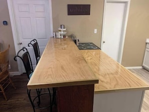 A kitchen with a wooden countertop, a stove, and a wall-mounted sign.