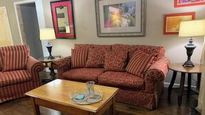 A living room with a patterned sofa, a wooden coffee table, and framed artwork on the walls. - ,Fern Corner: 4 bedroom / 2 Bath (Stillwater)