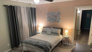 A bedroom with a bed, two bedside tables with lamps, a ceiling fan, and a door leading to another room. - ,Fern Corner: 4 bedroom / 2 Bath (Stillwater)