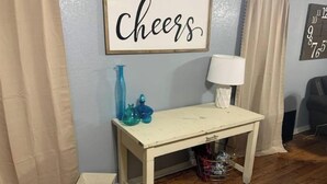 A room with a wooden floor, a white table with blue vases, a 'Cheers' sign, and a clock on the wall. - ,Newly re-finished 4 bedroom / 2 bath home (Stillwater)