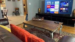 A living room with a television displaying a streaming service interface, a coffee table, and a sofa with a red cushion.