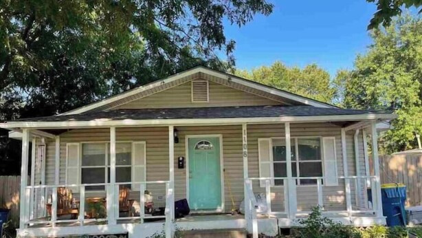 A single-story house with a front porch, a green door, and a small front yard.
