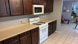 A kitchen with dark wooden cabinets, a white stove, and a microwave.