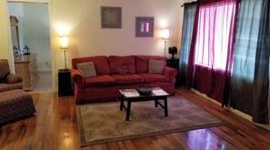 Una sala de estar con un sofá rojo, una mesa de centro y dos lámparas.