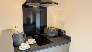 A compact kitchen with a black range hood, a kettle, a toaster, and a small countertop. - Retreat In The Hills - The Old Post Office (Malvern)