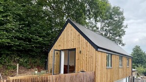 A wooden house with a sloped roof, a front door, and windows. - Retreat In The Hills - The Old Post Office (Malvern)
