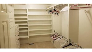 A walk-in closet with multiple shelves and hanging space, a mirror, and a coat rack. - Cowboys' Home with a Hot Tub (Stillwater)