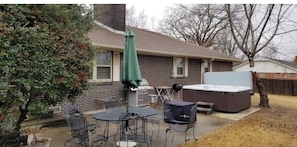 Een achtertuin met een jacuzzi, tuinmeubilair en een huis van baksteen.