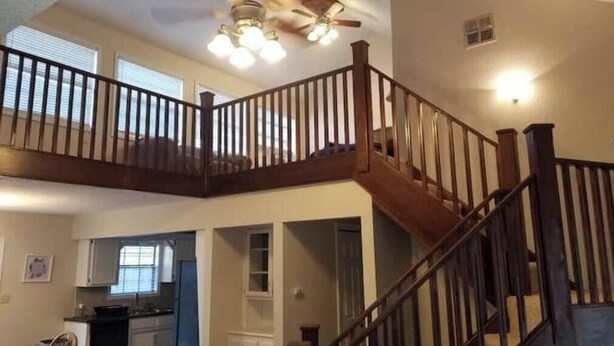 A spacious interior with a wooden staircase, a kitchen area, and a ceiling fan. - Crestwood Bungalow (Stillwater)