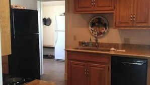 A kitchen with wooden cabinets, a black refrigerator, a dishwasher, and a tiled floor. - -Beautiful 4.5 BR / 4 Ba home with 2 car garage (Cushing)