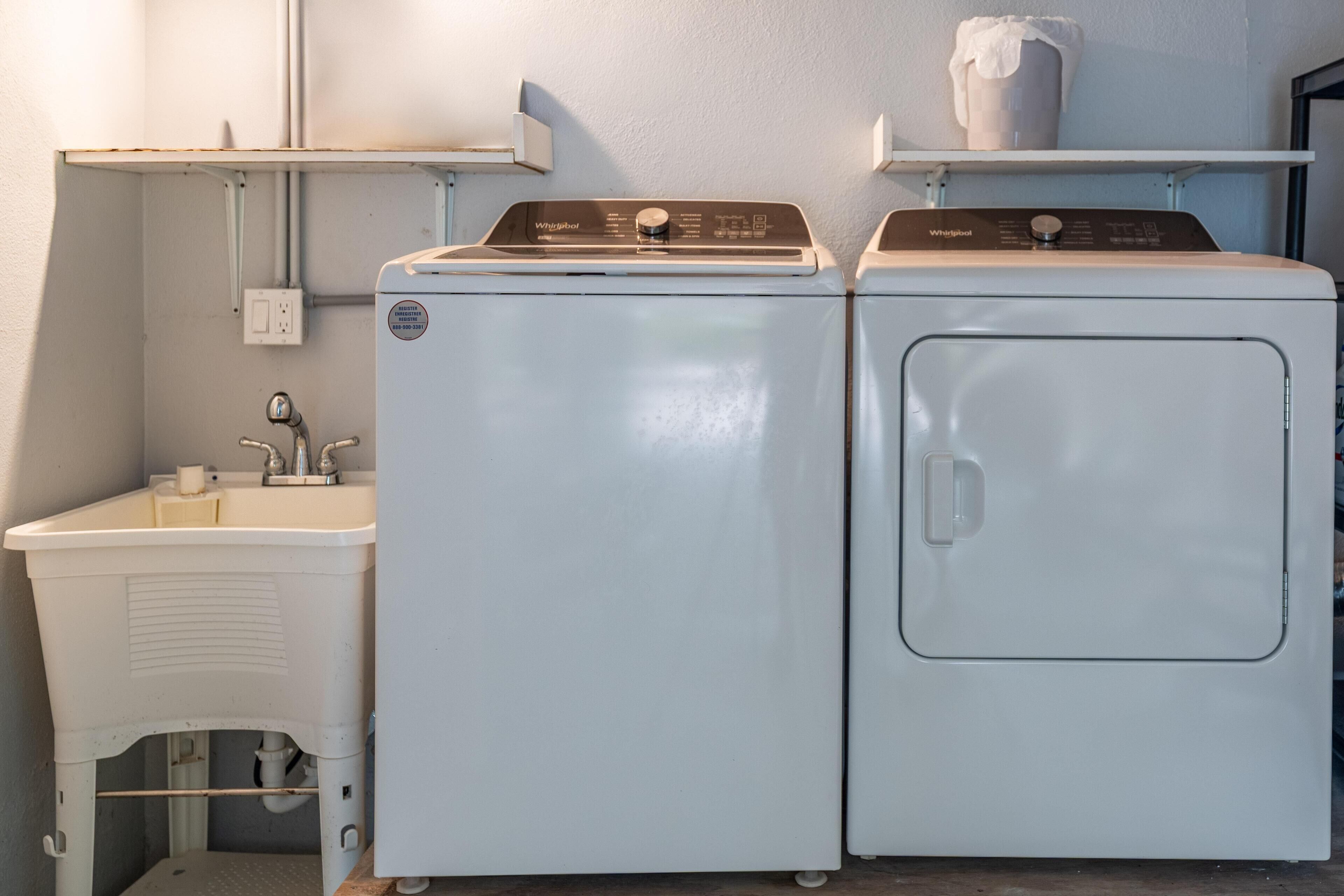 A laundry area with two Whirlpool washers and a sink.