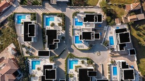 Ein moderner Wohnkomplex mit mehreren Schwimmbecken, verbundenen Gangwegen und einem Innenhof.