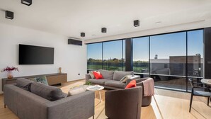 Ein modernes Wohnzimmer mit großem Fenster, Flachbildfernseher und Essbereich.
