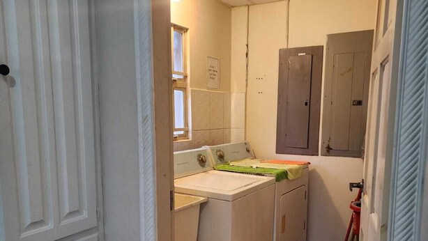 A compact laundry room with a washing machine, a drying rack, and a broom. - 3-bedroom townhome in lovely Couva with AC, fitness room (Couva)