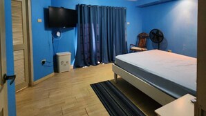 A bedroom with a bed, a television mounted on the wall, a fan, and a window with curtains. - 3-bedroom townhome in lovely Couva with AC, fitness room (Couva)