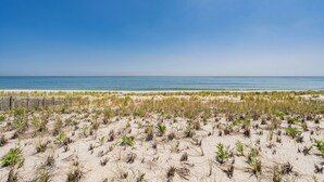 Une plage avec des dunes de sable et une clôture en bois au premier plan.