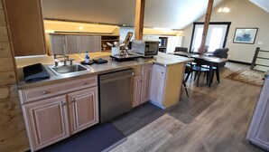 A modern kitchen with stainless steel appliances, wooden cabinets, and a dining area with a high ceiling and exposed beams. - Charming barn studio in peaceful Bellingham with AC (Bellingham)