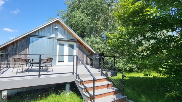A wooden cabin with a deck, outdoor furniture, and a staircase leading to a covered area. - Charming barn studio in peaceful Bellingham with AC (Bellingham)