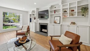 Una sala de estar moderna con chimenea, televisor y estanterías empotradas.