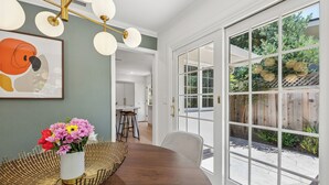Un comedor con una mesa de madera, un jarrón blanco con flores y un cuenco de mimbre.