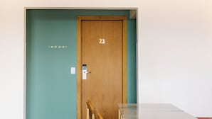 Une pièce avec une porte en bois portant le numéro 23, une petite table et une chaise.
