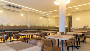 Un restaurant moderne avec des tables et des chaises hautes, un éclairage encastré et des motifs décoratifs sur les murs.