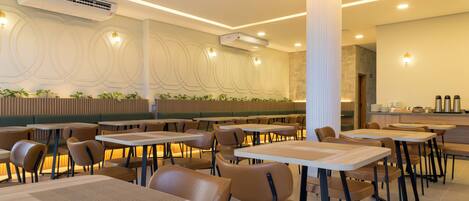 A modern restaurant with high tables and chairs, recessed lighting, and decorative wall patterns.
