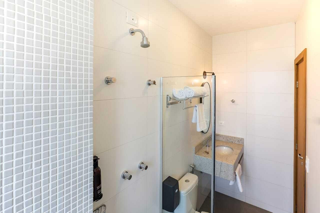 Un baño moderno con ducha de vidrio, inodoro y lavamanos con toallero.