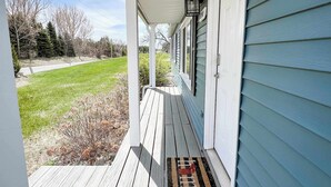 Une véranda en bois avec un paillasson, une boîte aux lettres et un lampadaire.