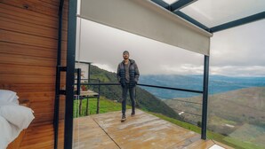 Una persona de pie en un balcón con vistas a un paisaje montañoso.