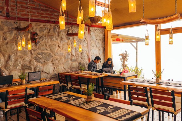 A rustic restaurant with stone walls, wooden tables, and hanging lanterns. - "Boutique lodge with jacuzzi and unique views - El Cedro Soñado (Patate)" (Patate)
