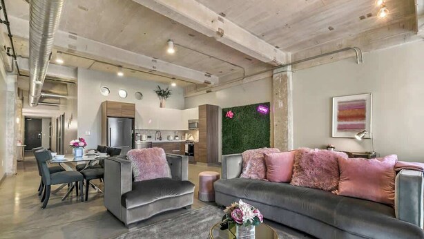Un salon moderne avec un canapé gris, deux fauteuils, une table basse et un coin repas comprenant une table et des chaises.