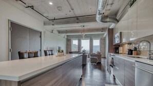A modern kitchen with a central island, stainless steel appliances, and large windows. - Resort-Style Loft w/ Free Valet (Dallas)