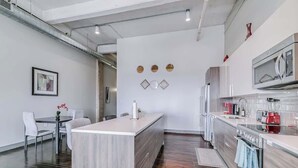 A modern kitchen with a central island, stainless steel appliances, and a dining area with a table and chairs. - Dallas Skyline Stay | Pool, Gym + Free Breakfast (Dallas)