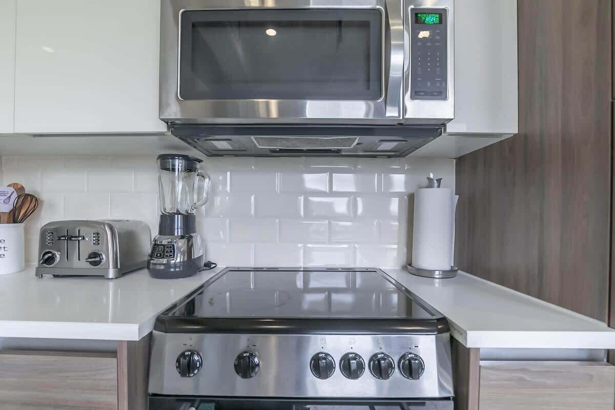 Une cuisine moderne équipée d’un four à micro-ondes en acier inoxydable, d’un grille-pain et d’un mixeur, le tout posé sur le plan de travail.